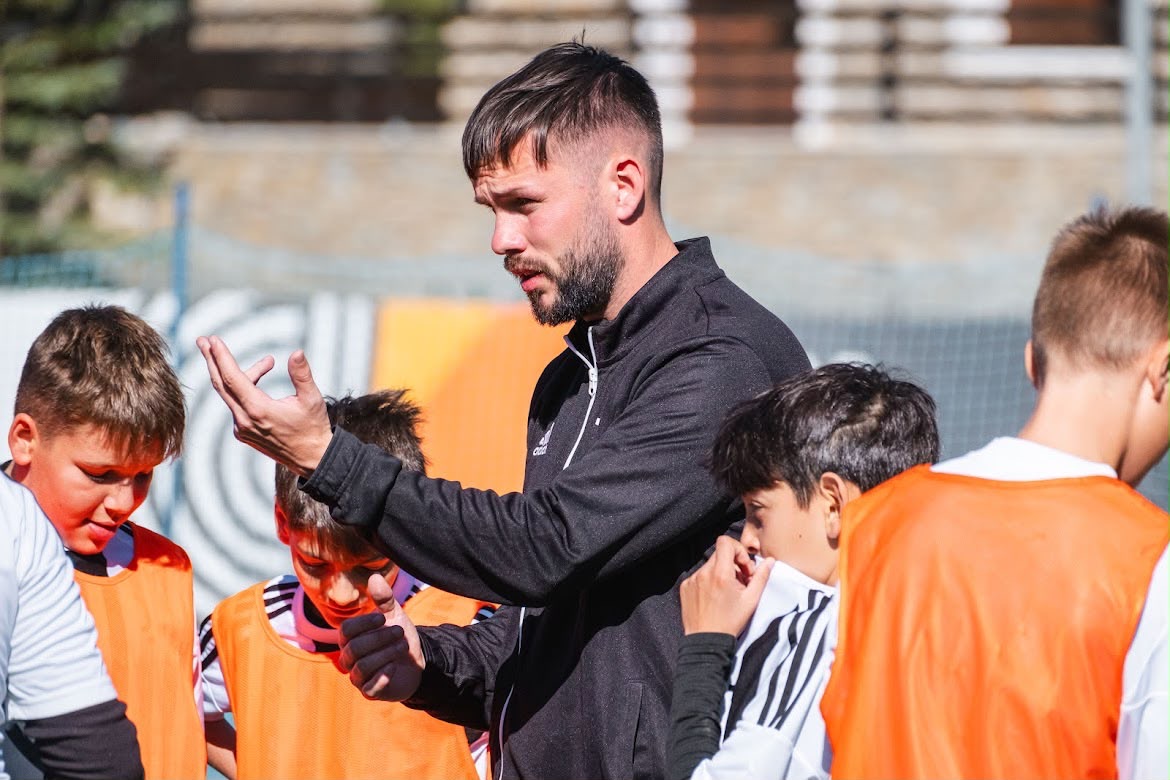 Dan Grimes explaining a coaching point to a group of young players in training bibs