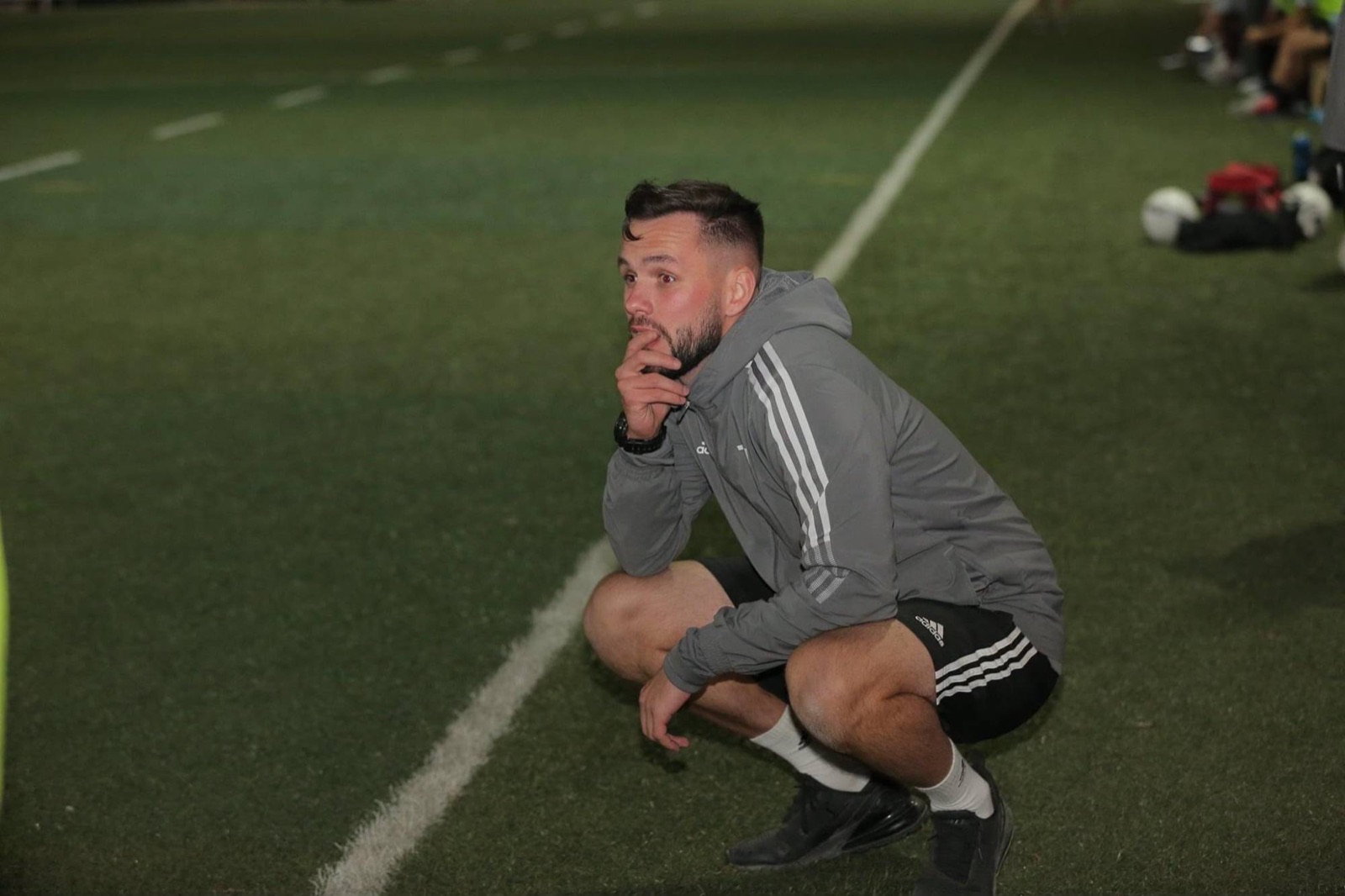 Dan Grimes crouching on the touchline, watching a session intently